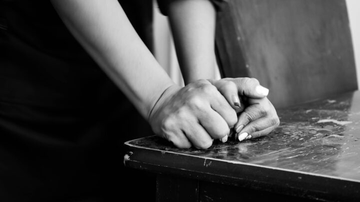 Two people's hands resting together on a table