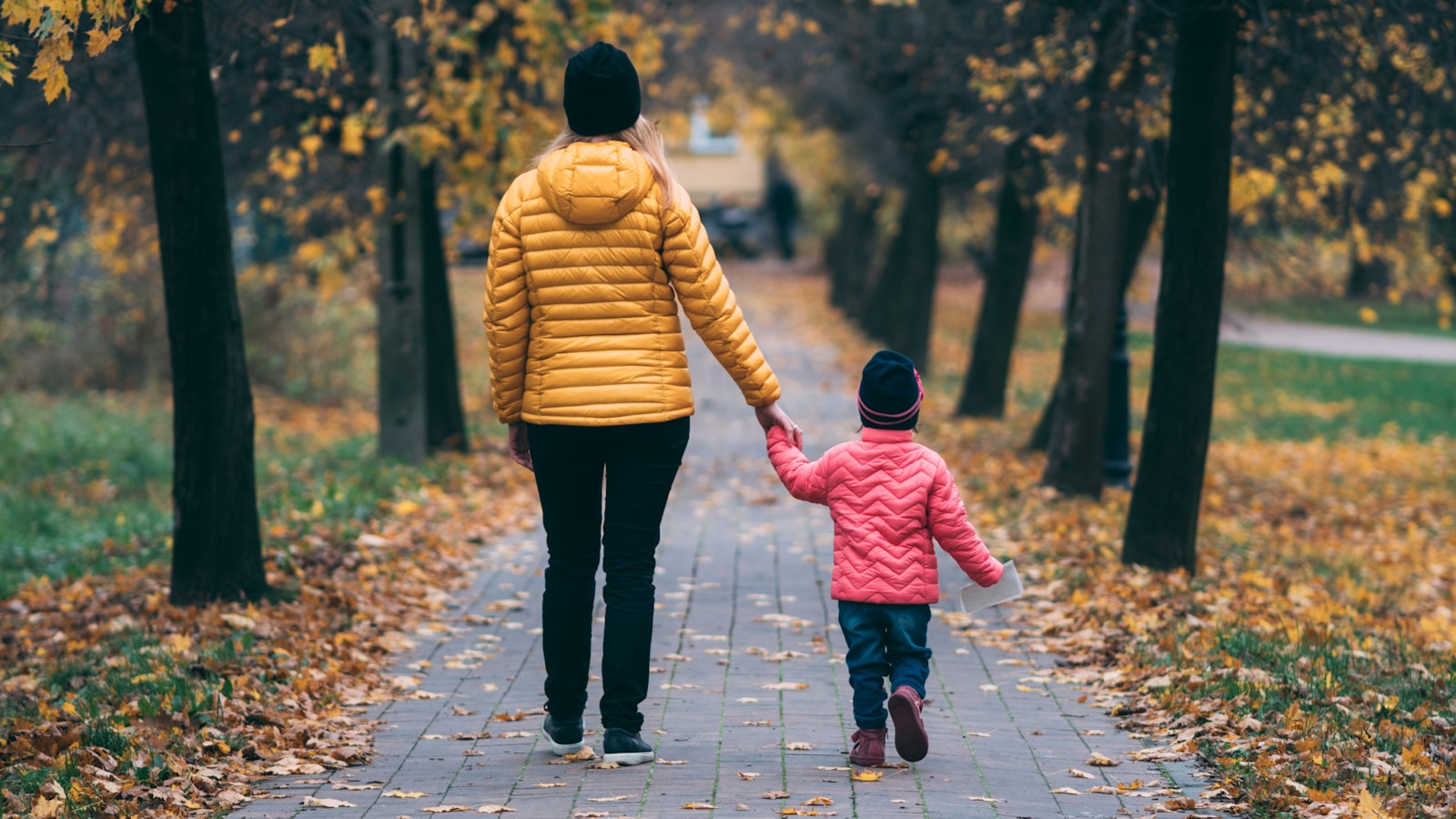 An adult and a small child holding hands while walking outdoors