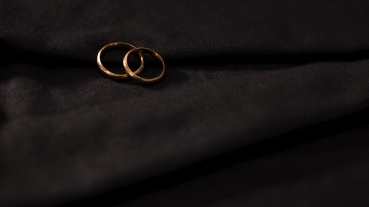 A plain gold band resting on a dark surface
