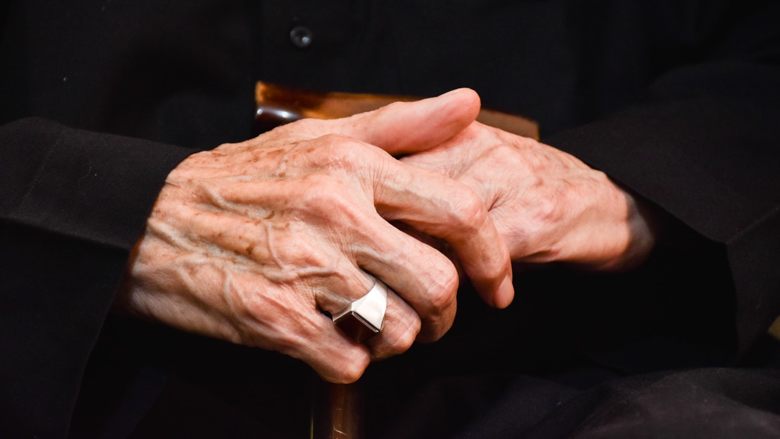 The hands of an older person resting in their lap