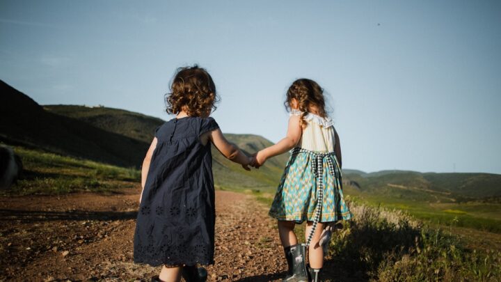 An adult and a child holding hands while walking