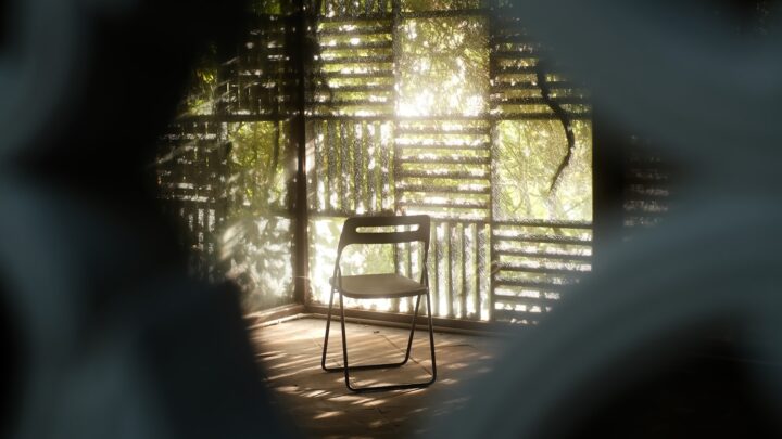 An empty wooden chair beside a window