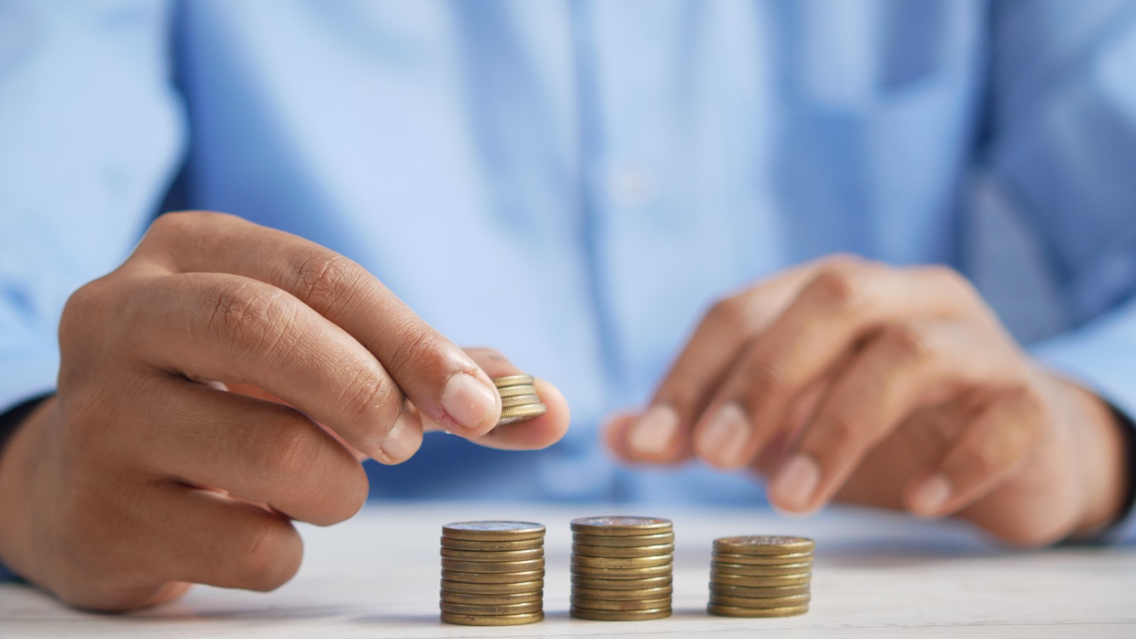 A hand placing a coin into a glass savings jar