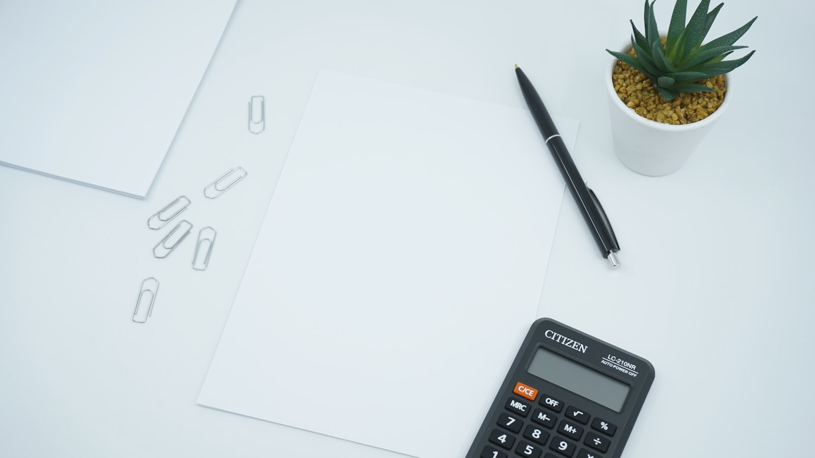 A calculator and pen resting on printed documents