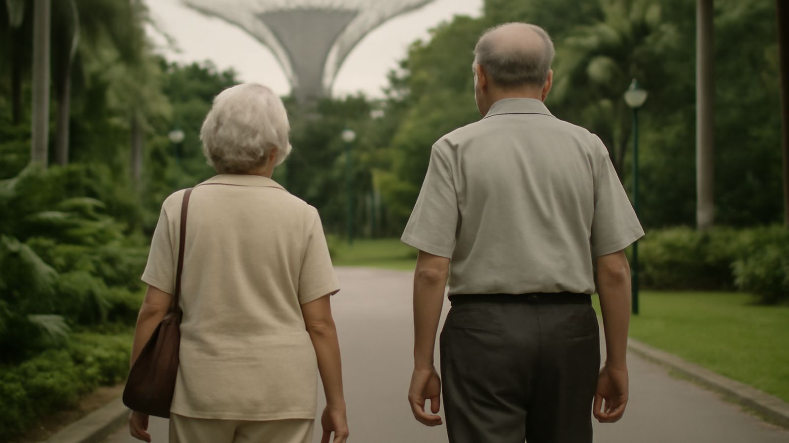 Two older people walking along a path in a park