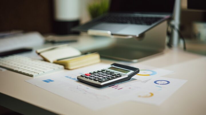 Household bills and a calculator on a wooden desk