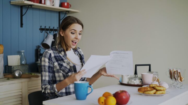 A person sitting at a kitchen table looking through paperwork