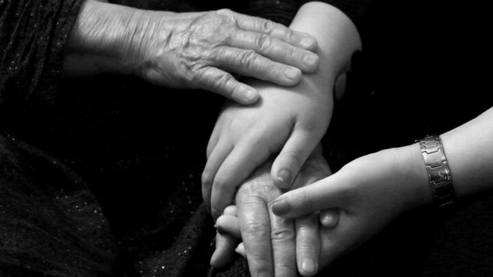 An older person's hand holding a small child's hand