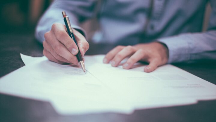Person reviewing and signing legal documents at a desk