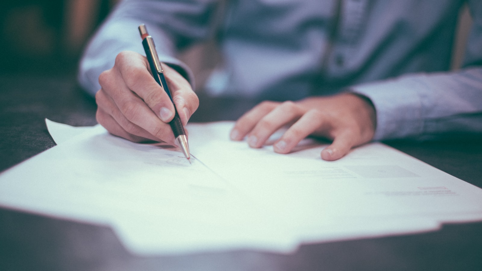 Person reviewing and signing legal documents at a desk