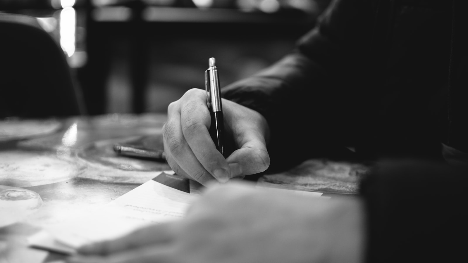 A person completing a printed form at a desk