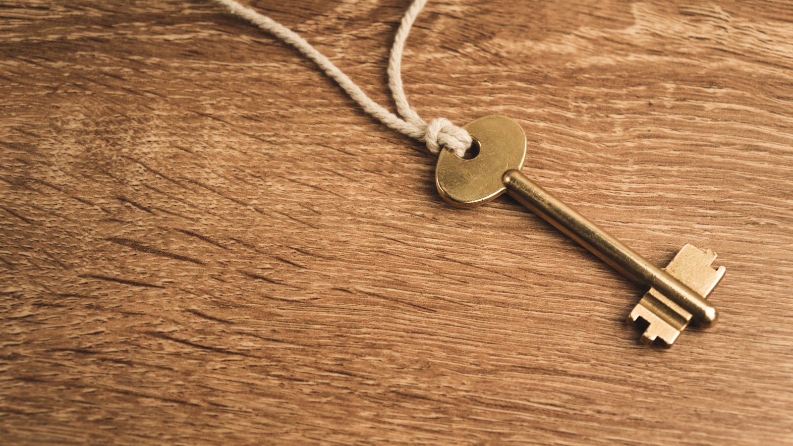 An antique brass key resting on a worn wooden surface