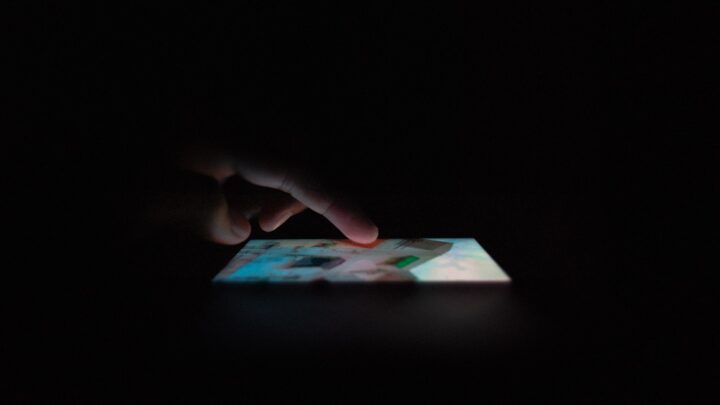 A pair of hands holding a mobile phone in a dimly lit room