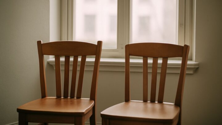 Two empty wooden chairs beside a bright window