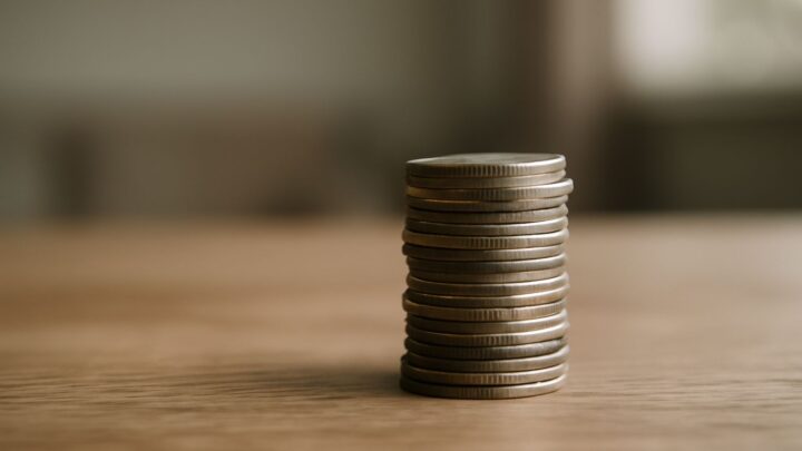 A small stack of coins resting on a wooden surface