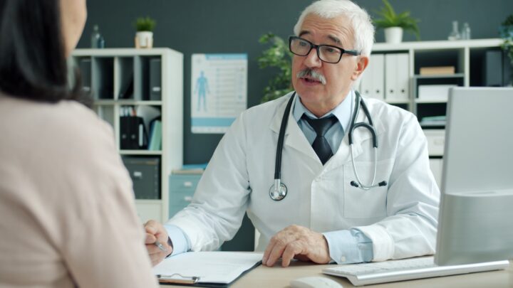 A medical professional talking with an older patient in a consultation room