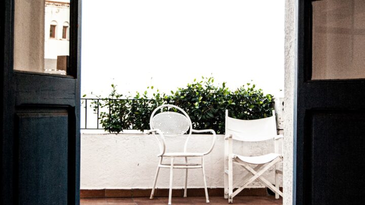 Two empty chairs on a balcony overlooking greenery