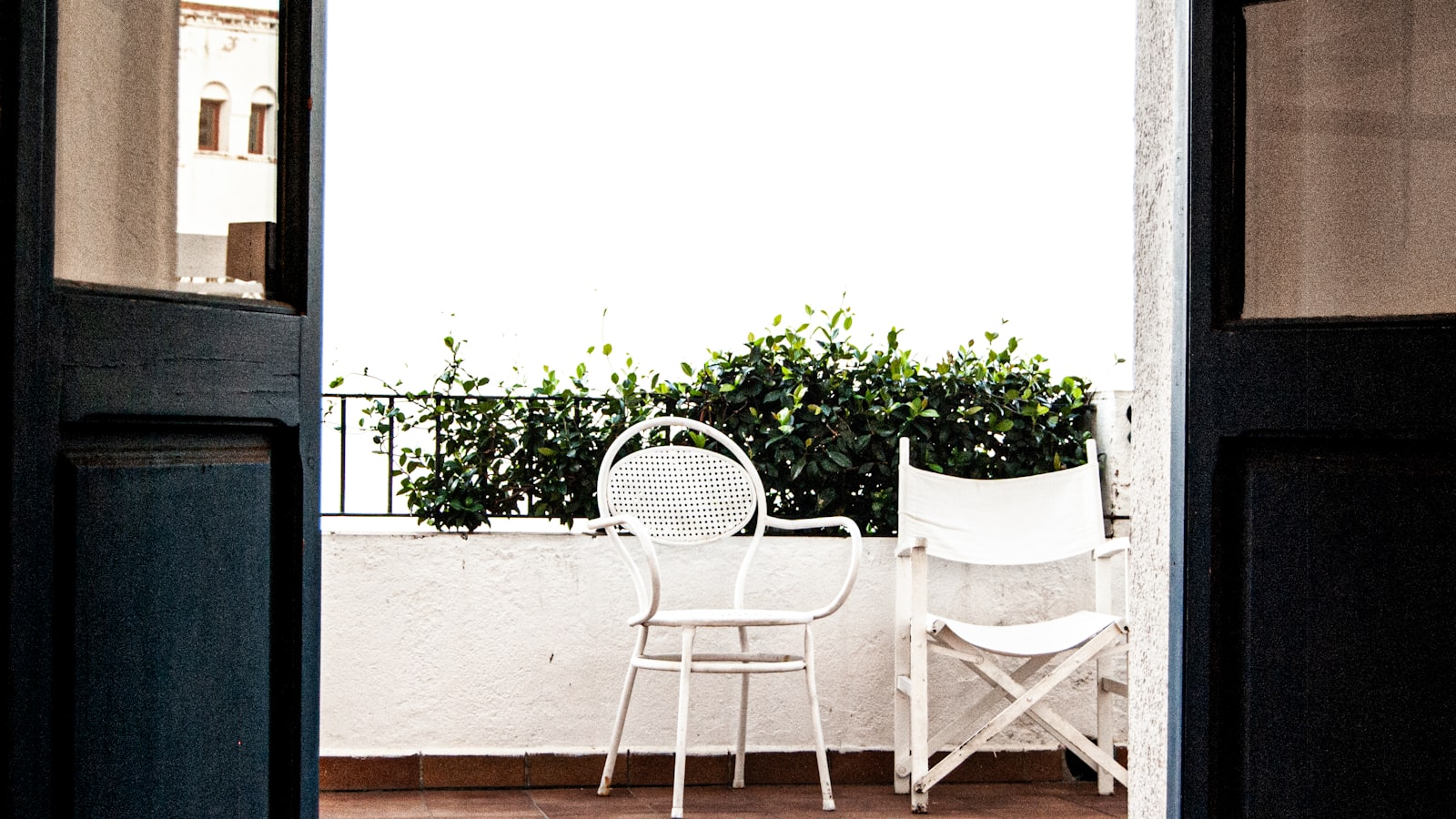 Two empty chairs on a balcony overlooking greenery