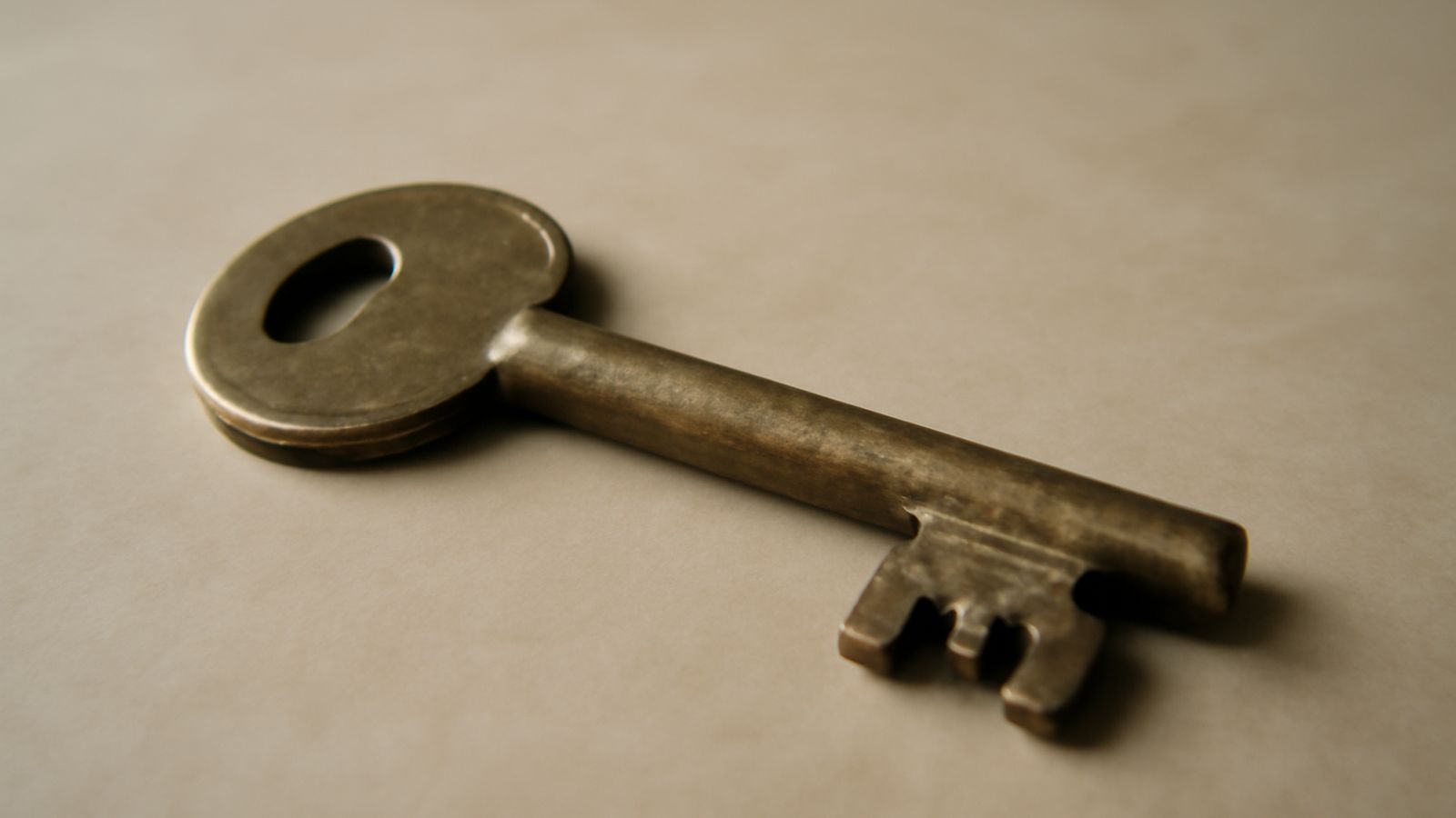 A weathered brass key resting on a plain table