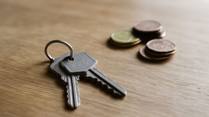 A set of keys and coins resting on a wooden surface