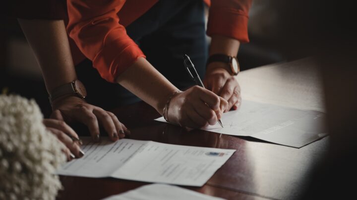 Couple signing an agreement with a pen on a desk
