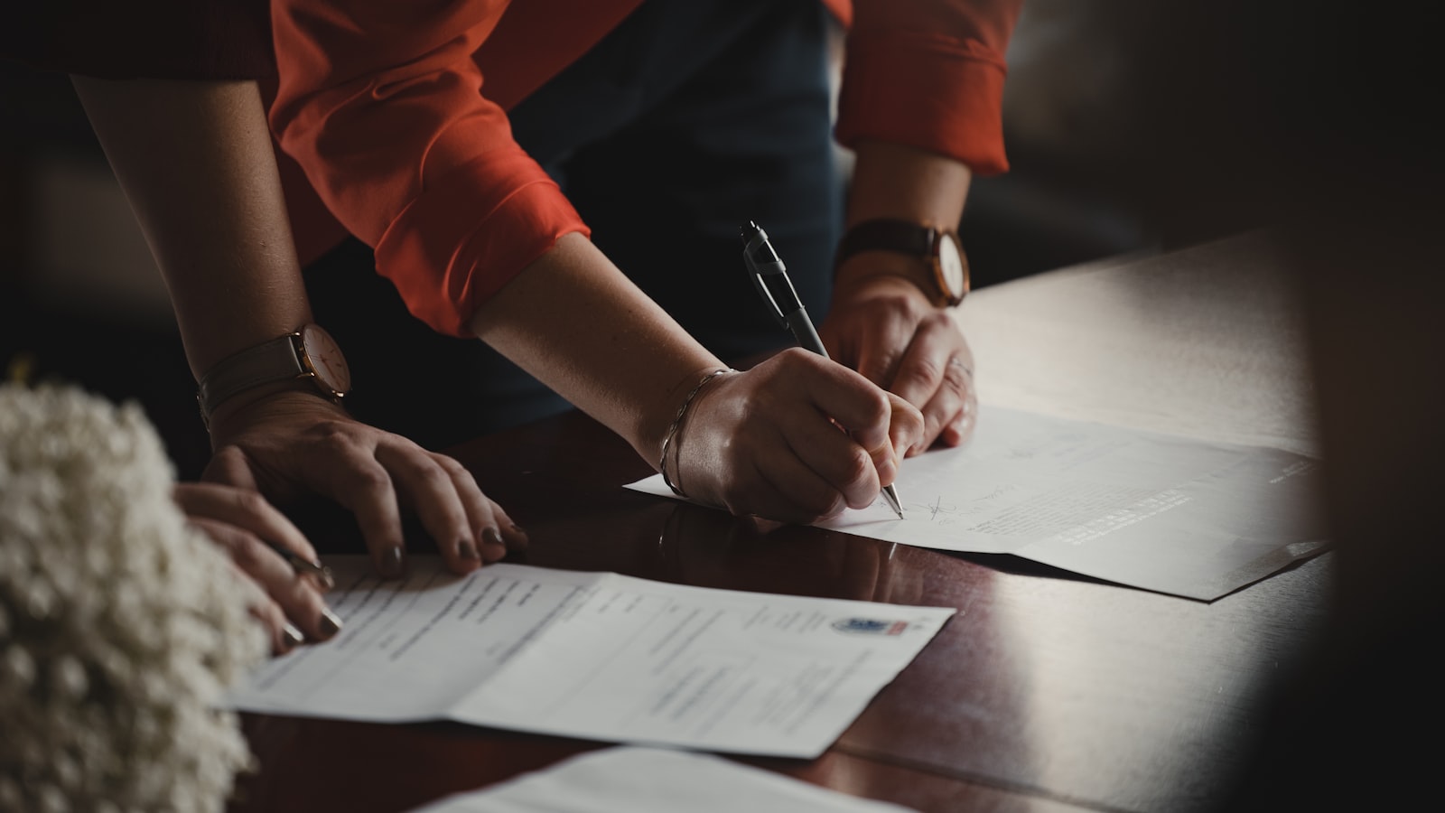 Couple signing an agreement with a pen on a desk