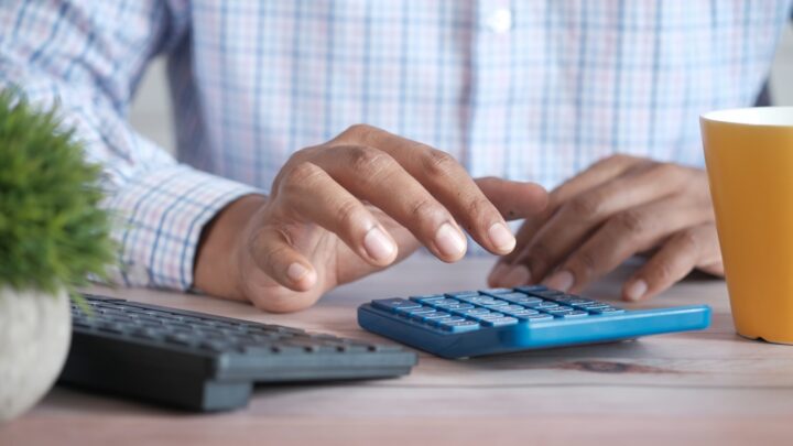 A person going through bills and statements at a desk with a calculator