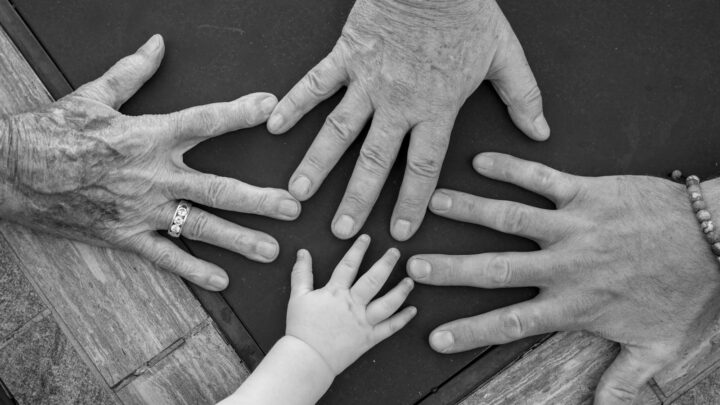Adult and child hands resting together on a wooden table