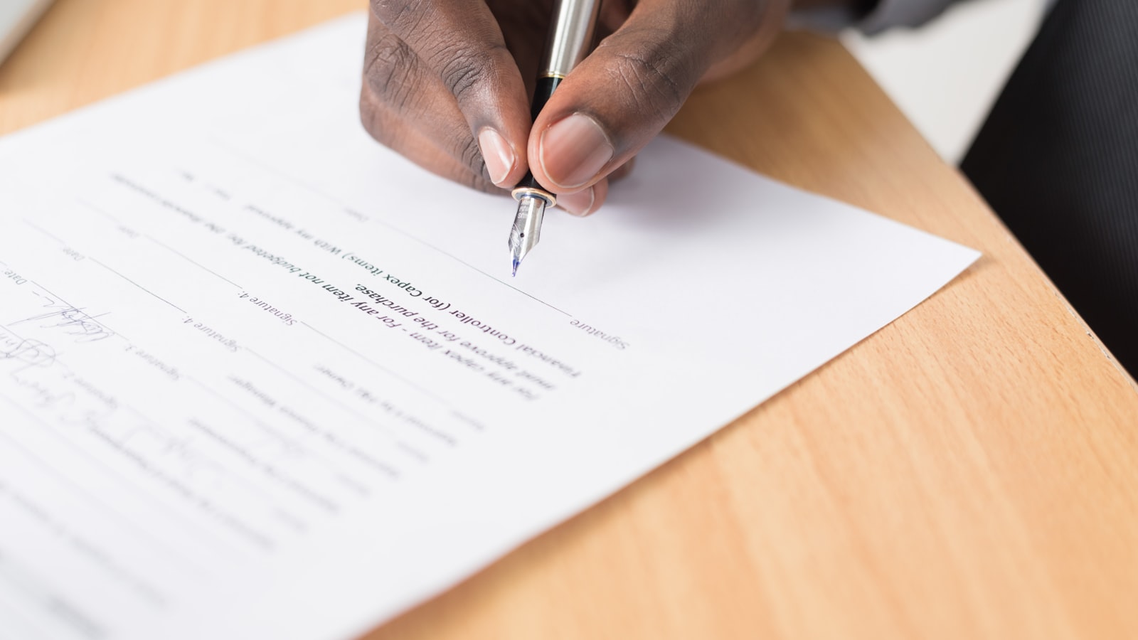 Two people signing an agreed document across a table