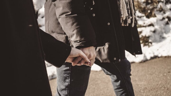 An adult and a small child holding hands outdoors