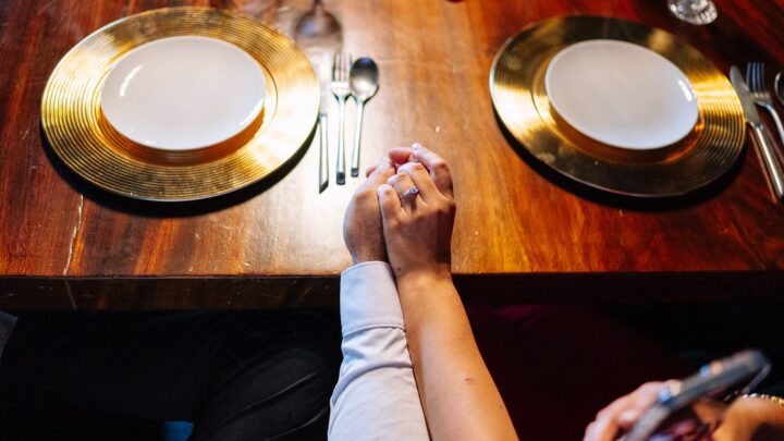 Two adults holding hands resting on a wooden table