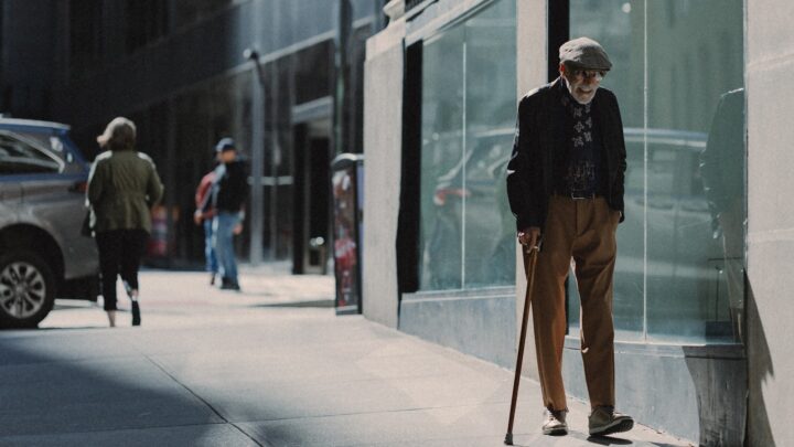 An older person's hands resting on a walking stick