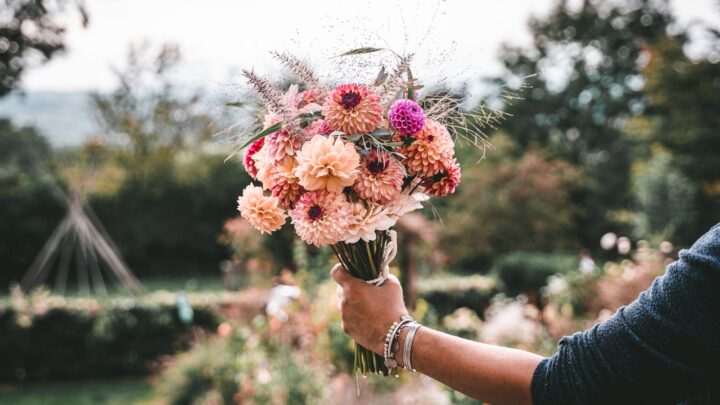 A pair of hands holding a small bouquet of white flowers