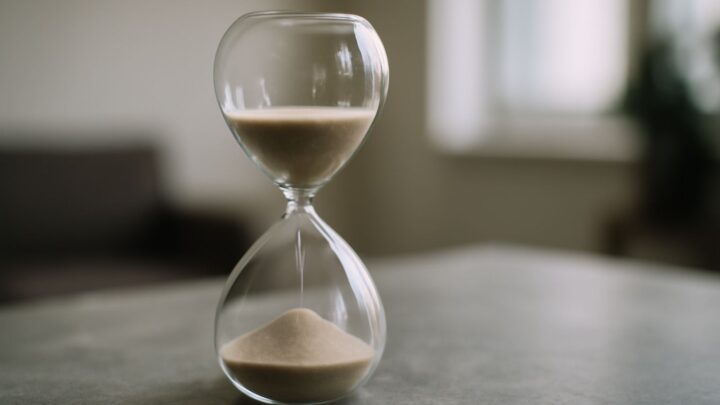 An hourglass standing on a plain stone surface