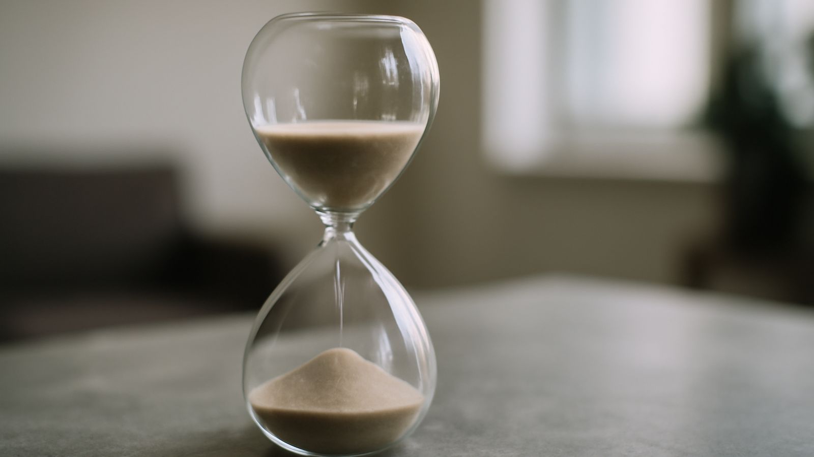 An hourglass standing on a plain stone surface