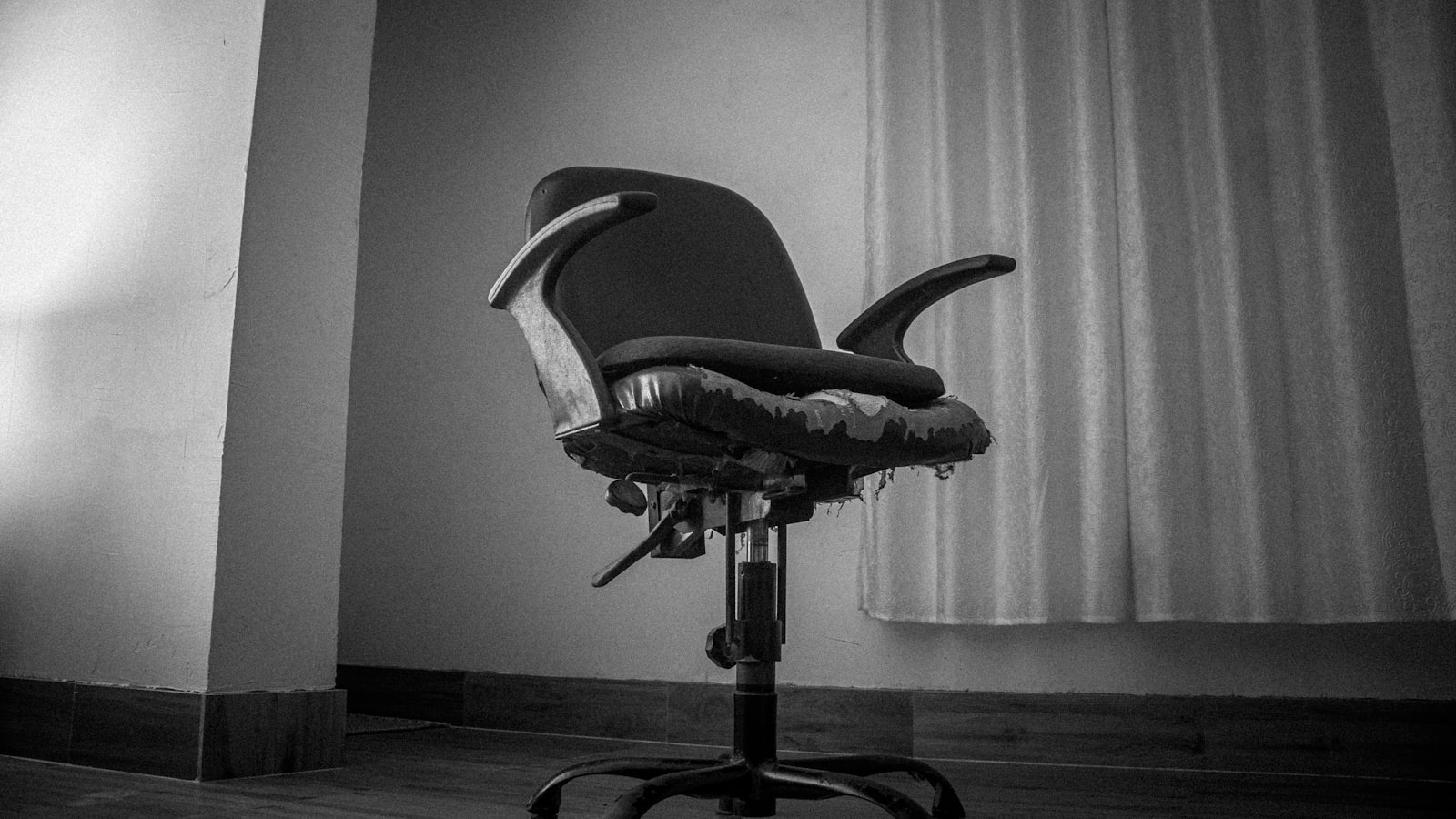 An empty desk and chair beside a window