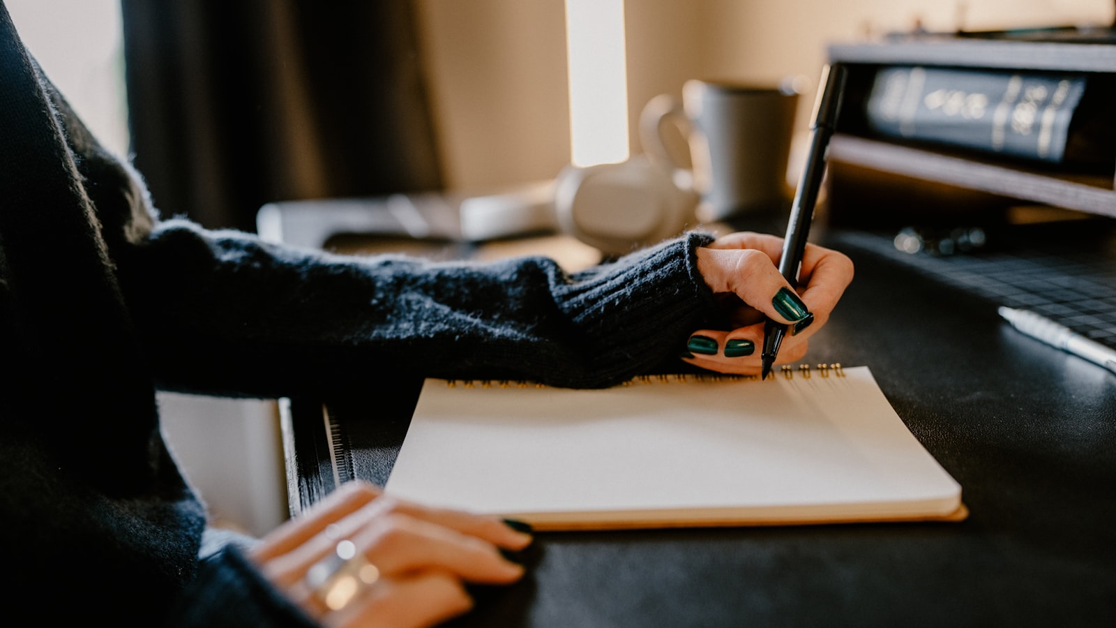 A person writing on paper at a wooden desk